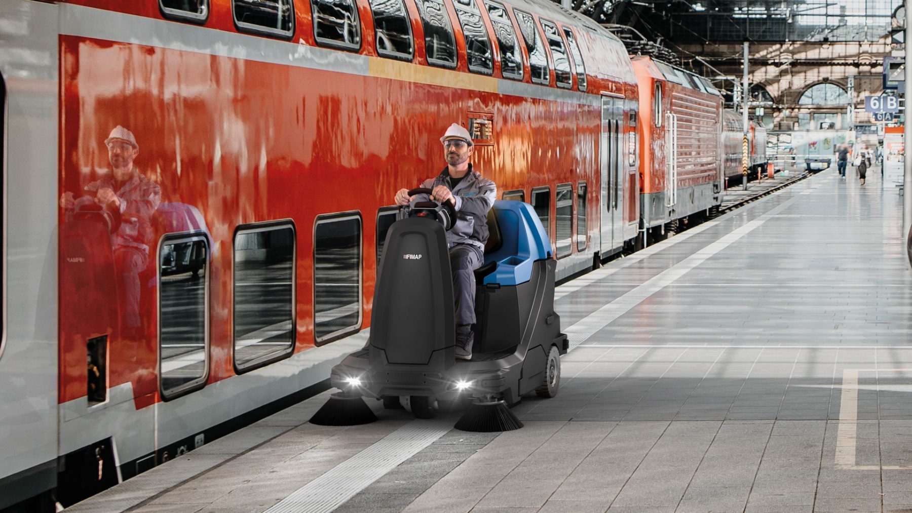 Sweeper cleaning a railway station platform beside a train