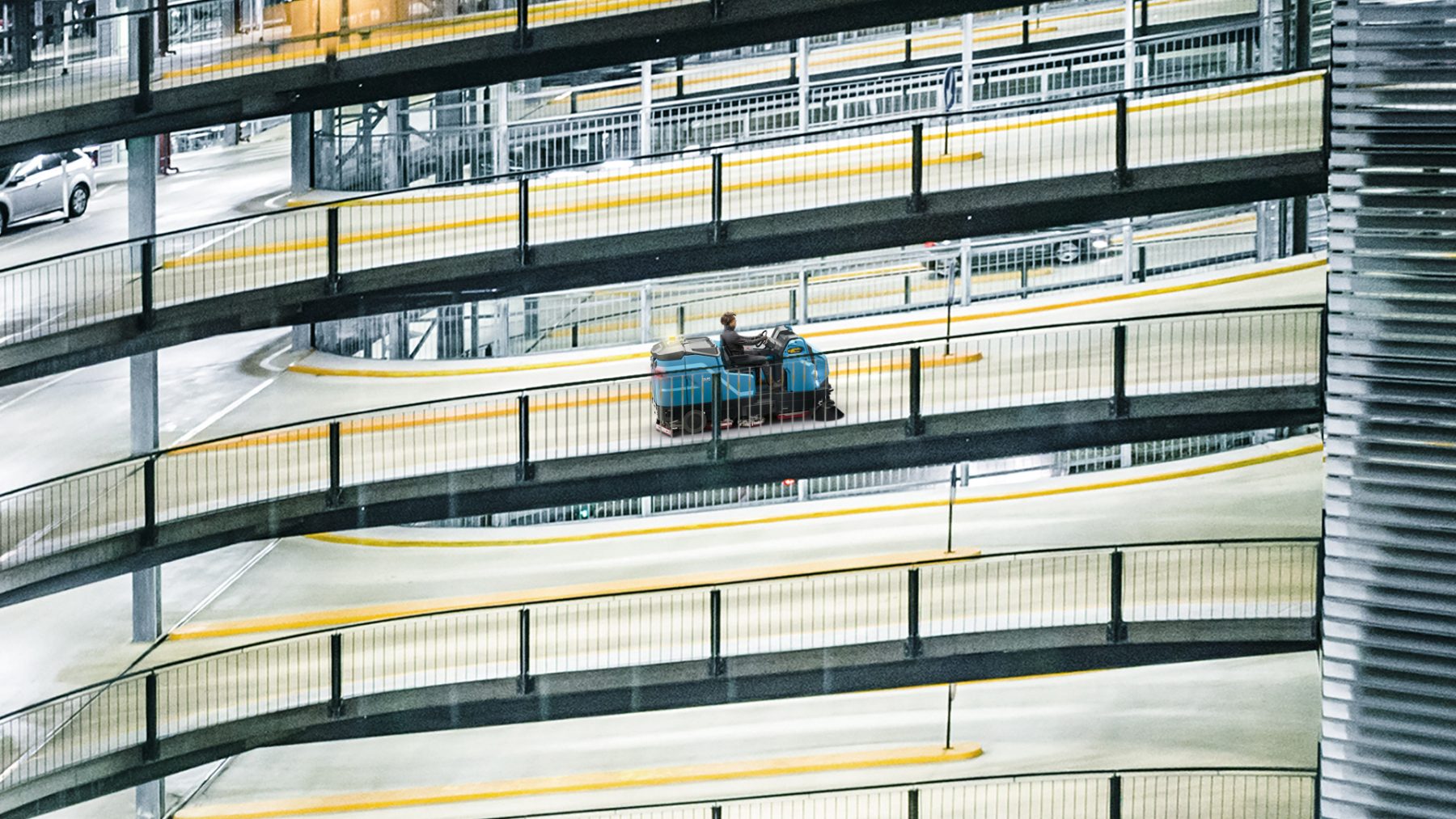 Ride-on machine cleaning a ramp inside a multi-level car park