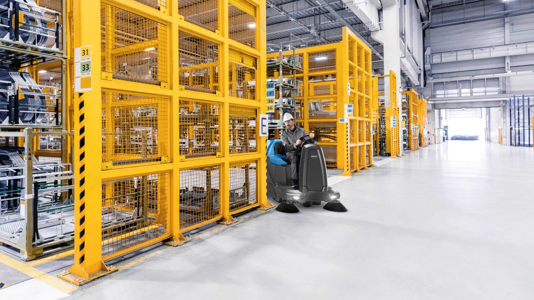 Ride-on sweeper hire working a warehouse aisle