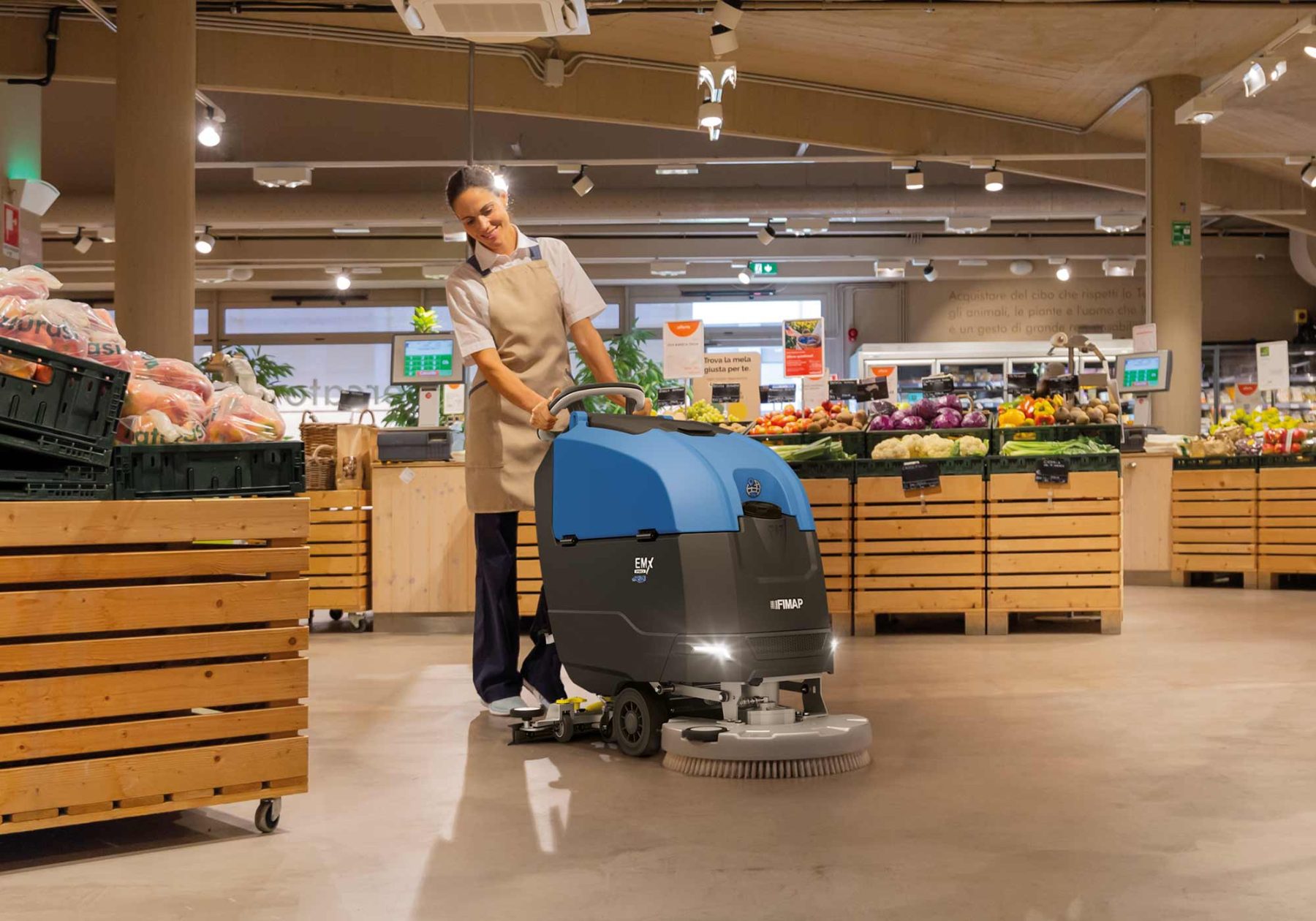 Walk-behind scrubber cleaning a polished supermarket floor between produce displays