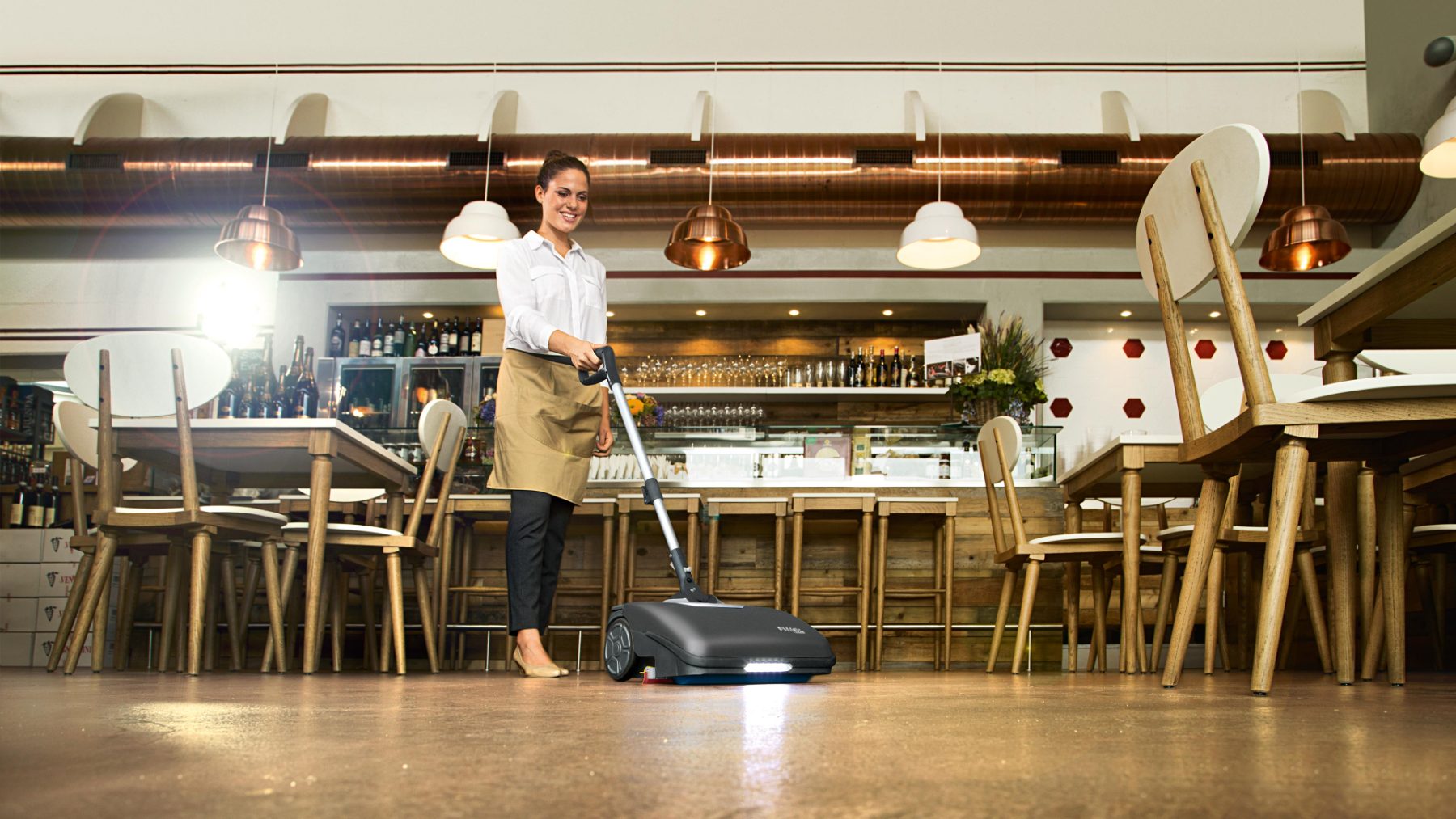 Walk-behind sweeper cleaning a cafe floor between service